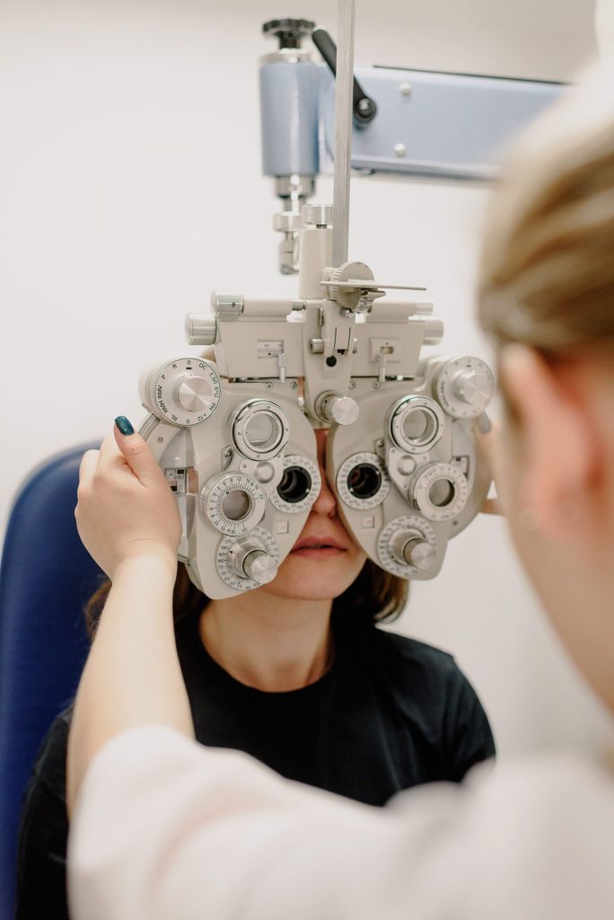 Ophtalmologue (visage non identifiable) réglant un équipement médical tout en effectuant un examen de la vue sur un patient dans une clinique moderne, en plein travail.