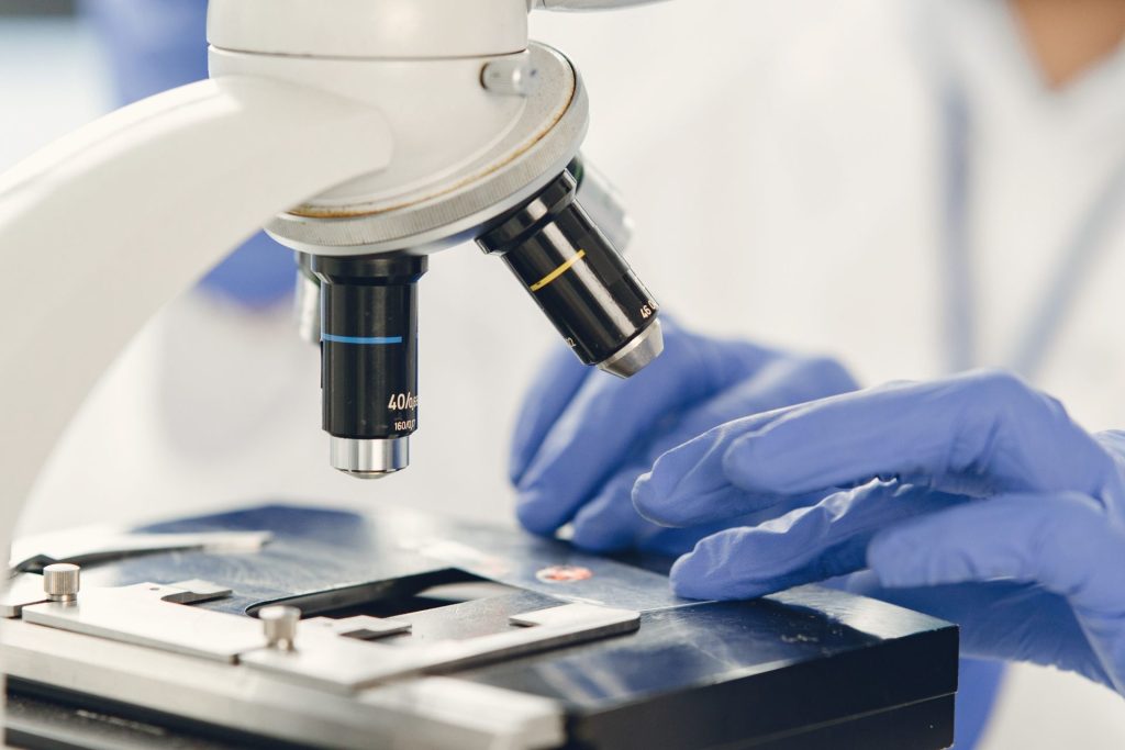 Vue en gros plan d'un scientifique examinant un échantillon au microscope dans un laboratoire.
